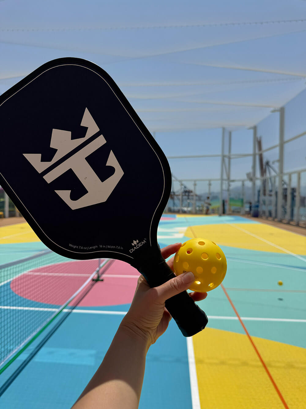 A Royal Caribbean pickleball paddle and ball on the sportsplex court, taken during Legend of the Seas' preview sailing